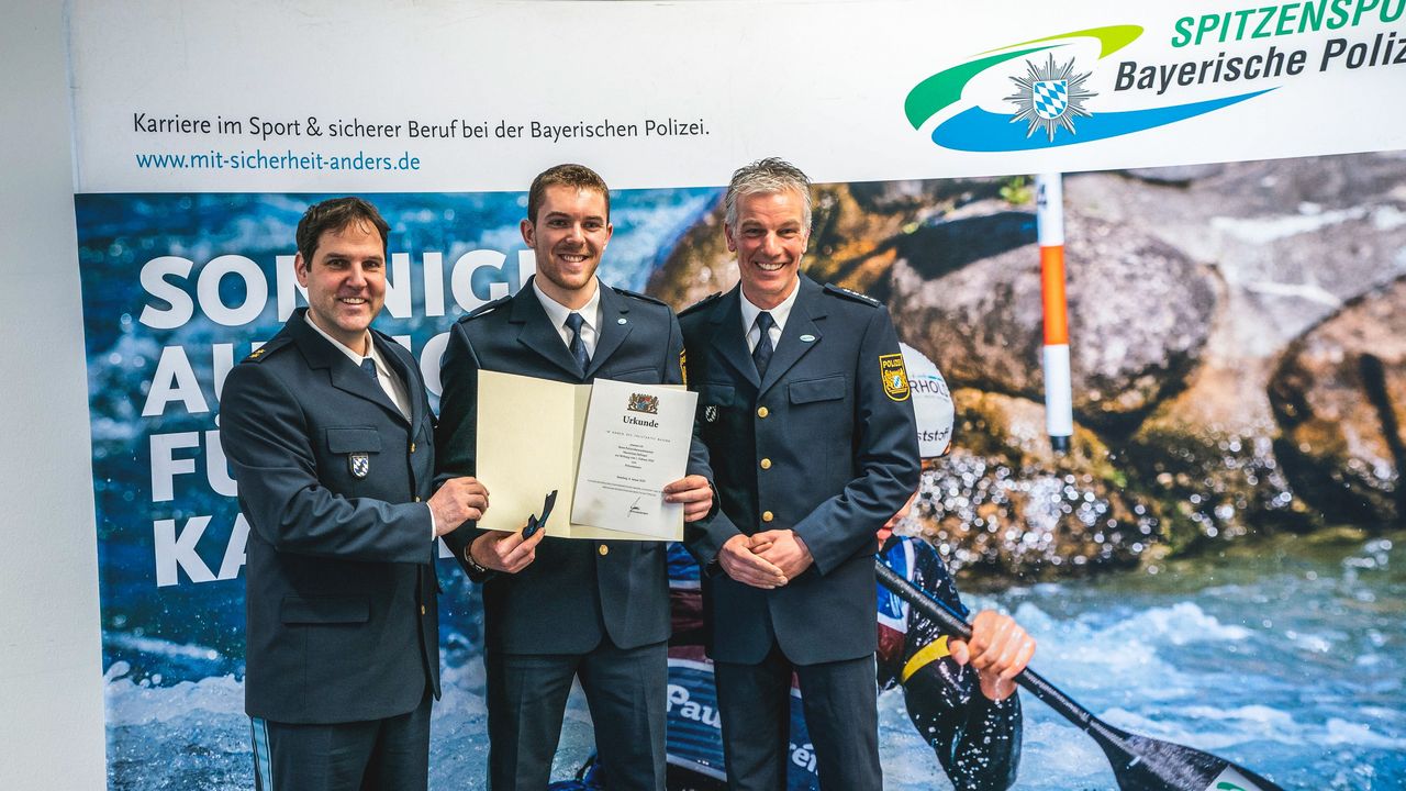 Foto: Bayerische Polizei / Maximilian Dallinger (Mitte) bei der Urkundenübergabe zur Enennung zum Polizeimeister.