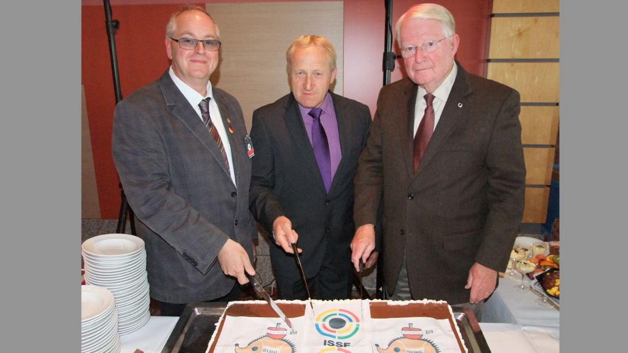 Foto: Michael Eisert / Zum 20-jährigen Jubiläum schnitten DSB-Vizepräsident Jugen Stefan Rinke, Willi Grill und Gary Anderson (beide ISSF) eine Torte an.